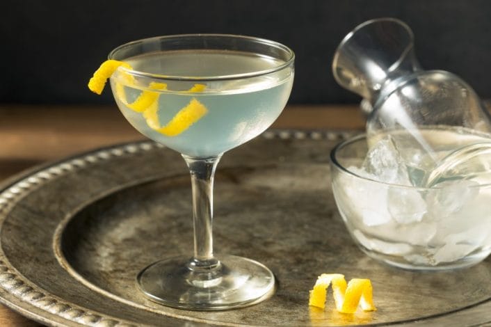 Champagne saucer sits on a silver tray, garnished with a lemon twist. 