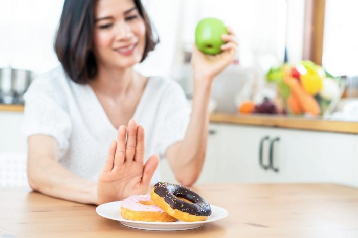 Woman rejects a plate of donuts and chooses apple instead. 
Jpg: bad-donuts
