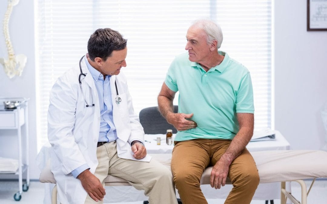 Man discussing digestive discomfort with his doctor.