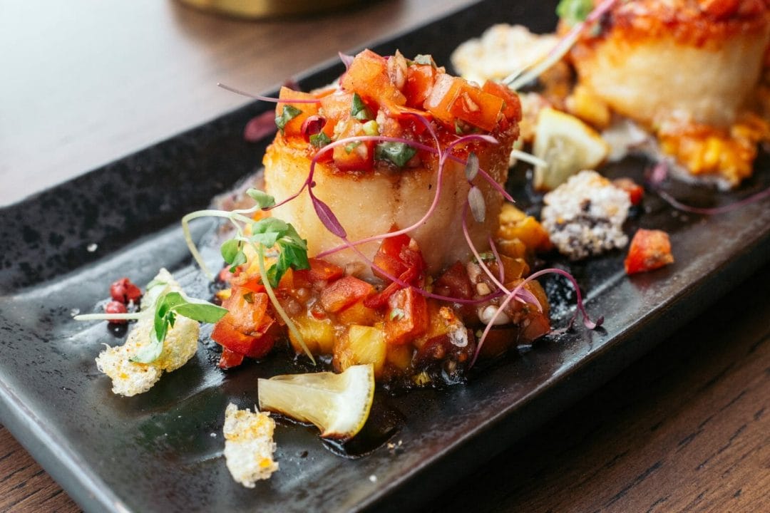 The Pickled Beet Plated seafood dish Beautifully plated and colorful scallops dish on black plate | The Pickled Beat
