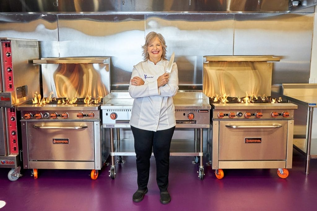 The Pickled Beet Miami Gluten-Free Kitchen, Chef Liz standing in new commercial kitchen in white chef coat in front of new commercial kitchen appliances